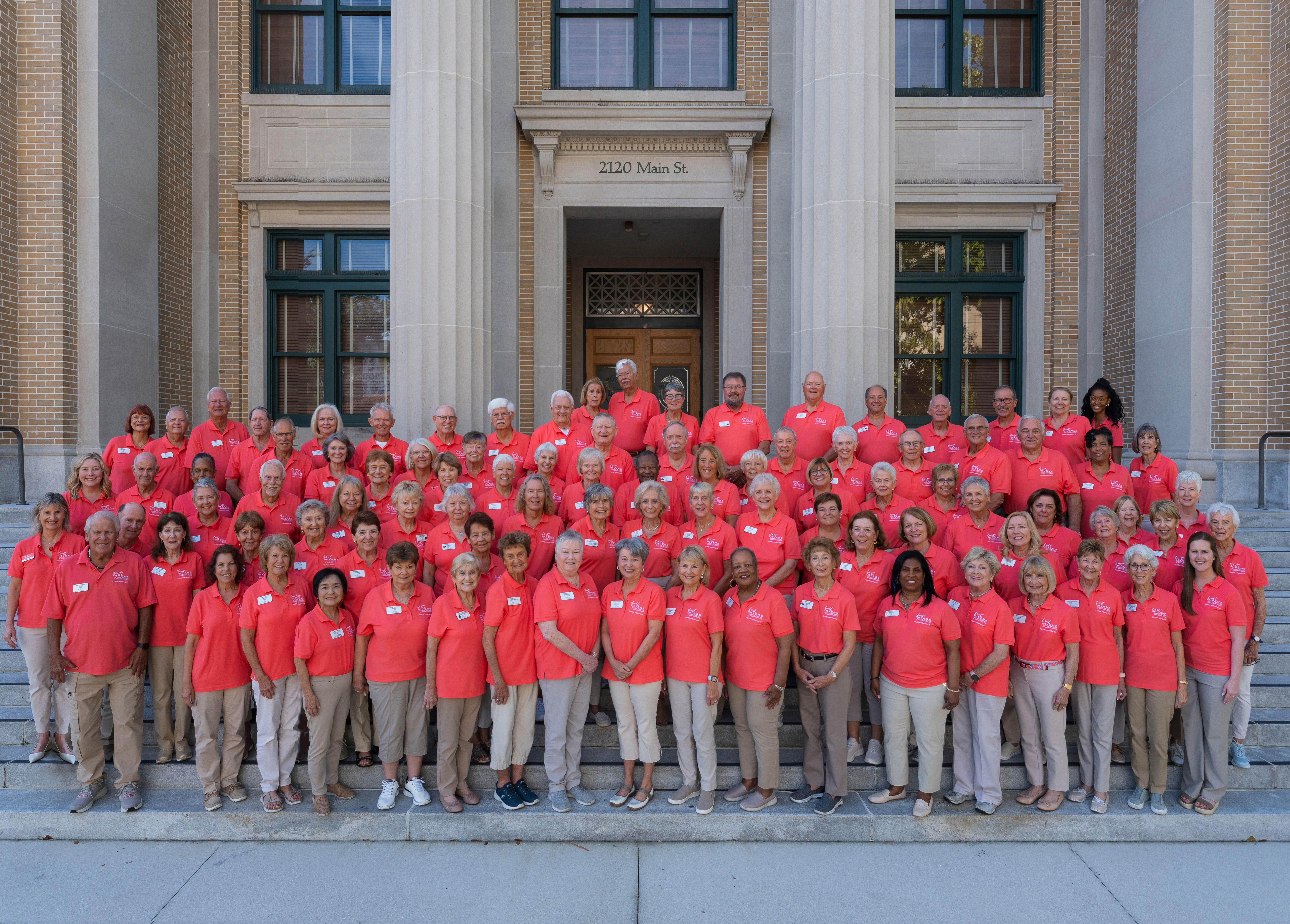 Group photo of volunteers wearing coral shorts on steps