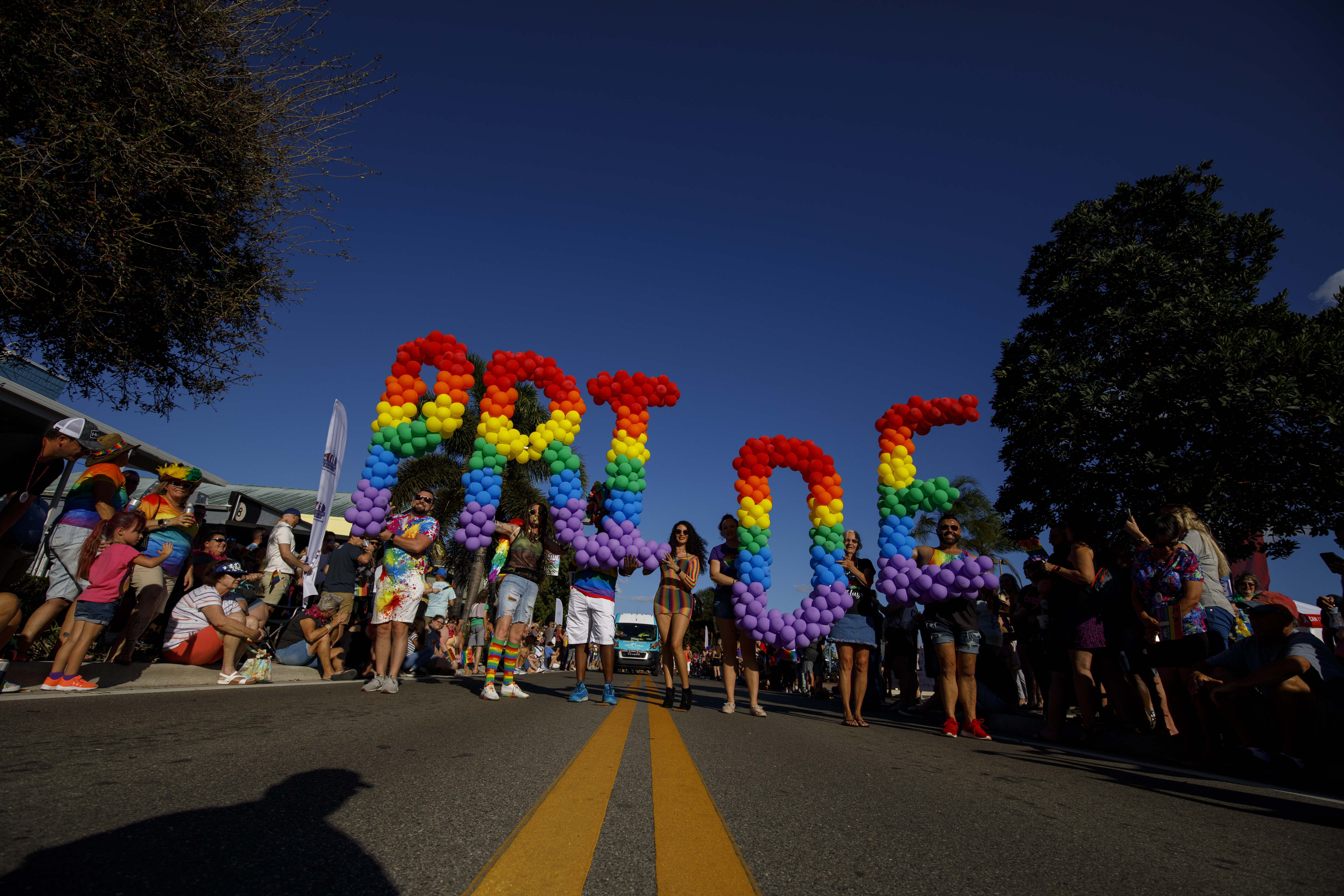rainbow colored baloons spelling out Pride in a parade