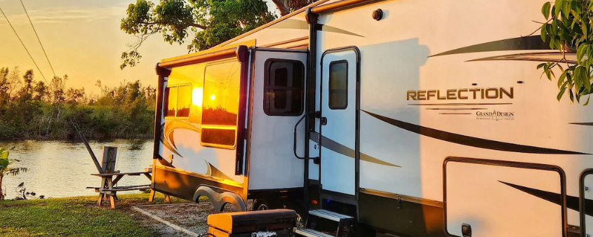 camper by river at sunrise