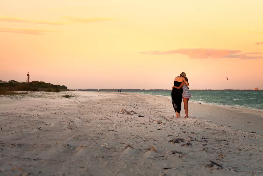 Two people hugging on a beach at sunset