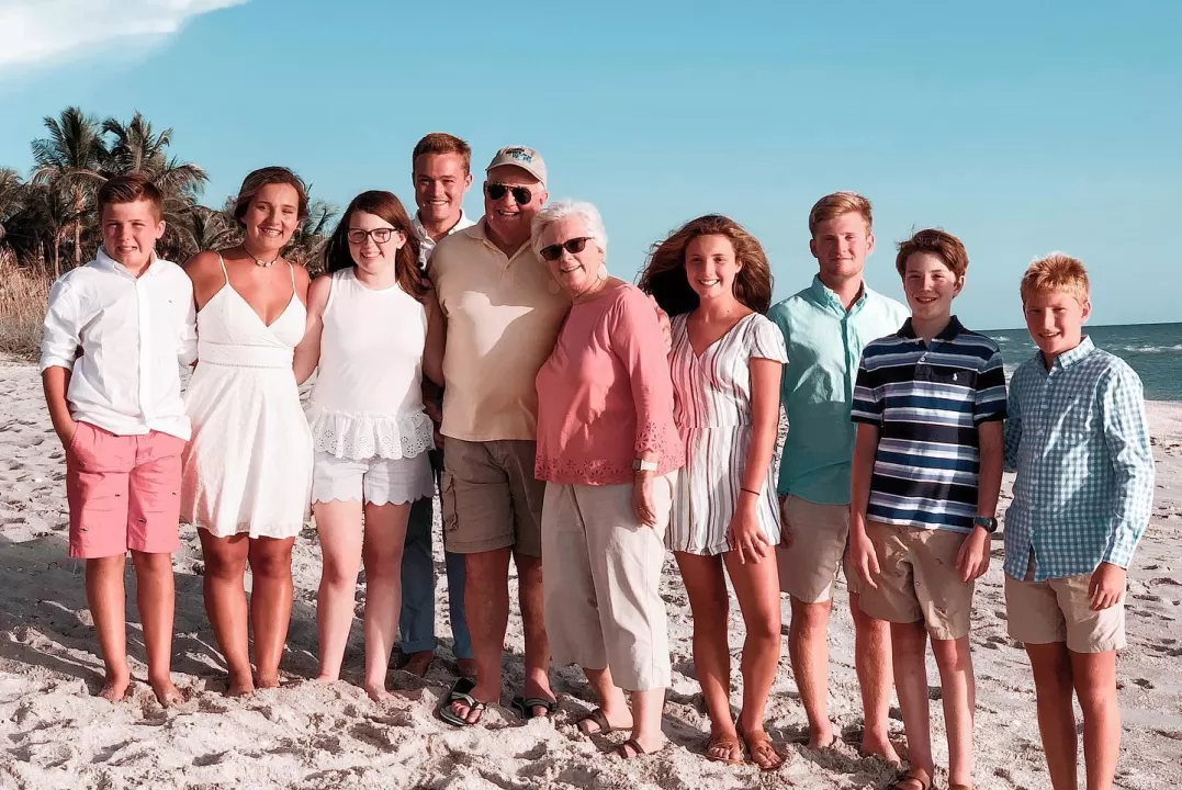 Family standing on top of a sandy beach