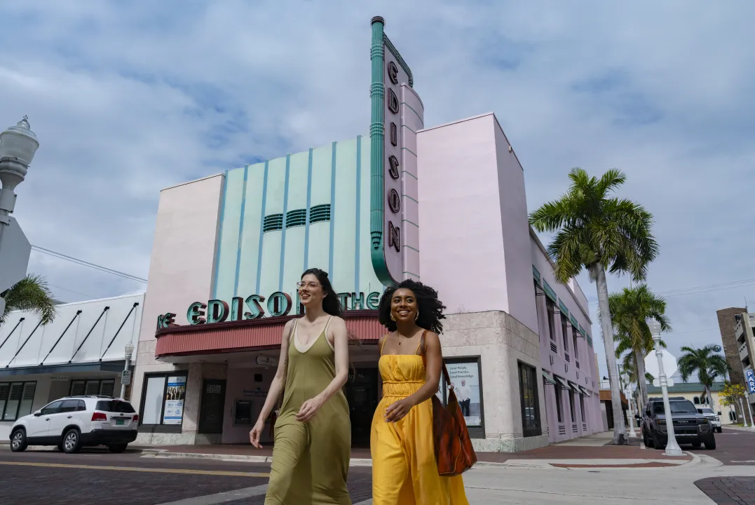 Two women stand outside the pink Art Deco facade of the Edison Theatre downtown.