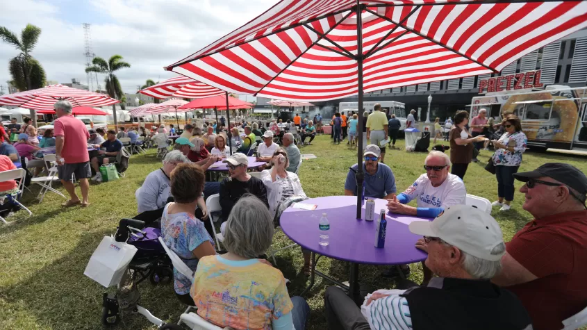 Attendees gather in one of our several food courts at a table in the shade of an umbrella.