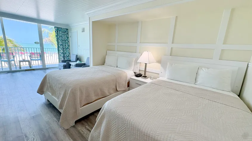 yellow wall with two double beds in a hotel room large sliding glass door overlooking the beach