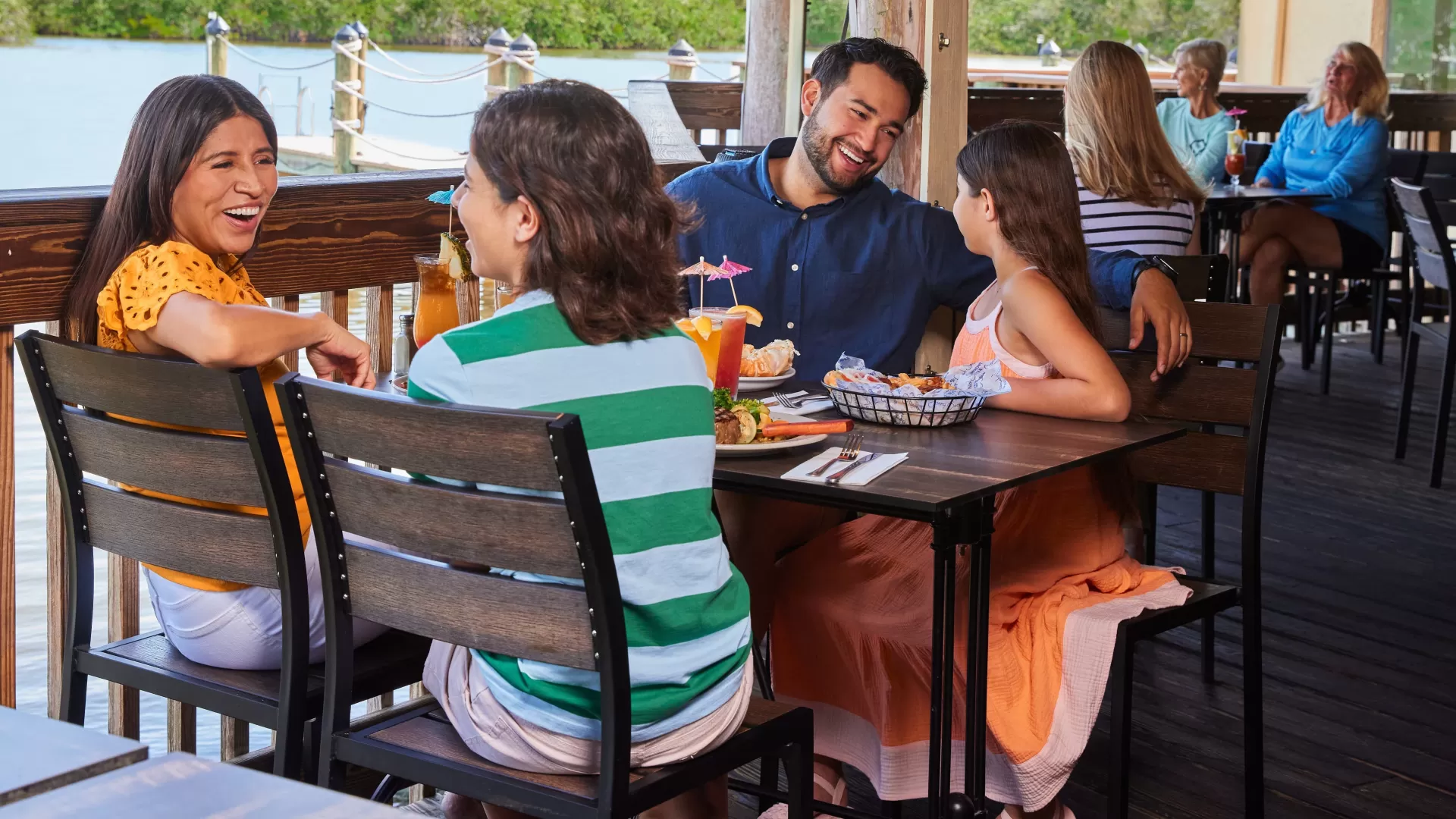 A family enjoys a waterfront meal on a covered patio at Coconut Jacks