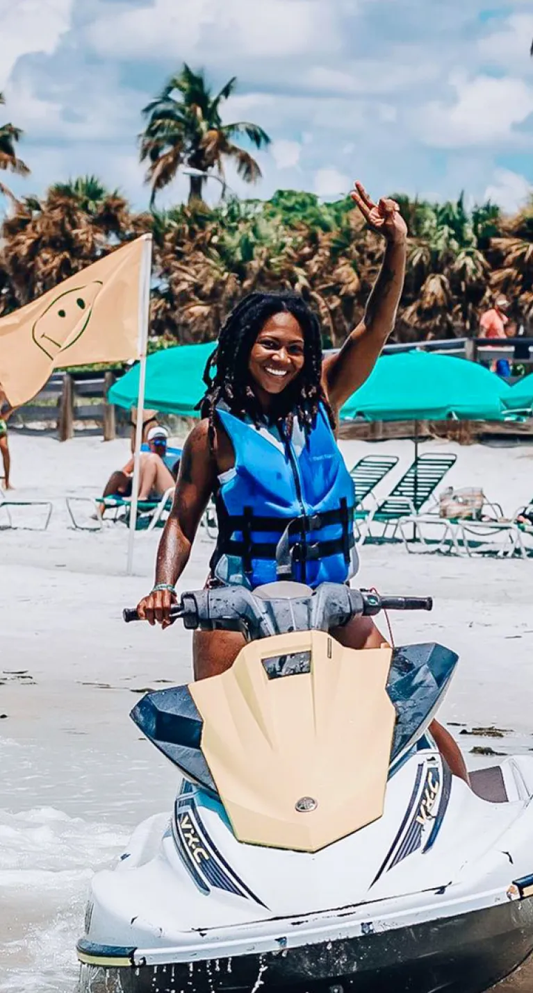 Woman rides a Jet Ski near the beach.