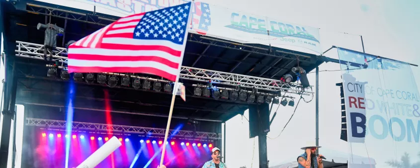 A crowd of people at a concert waving american flags