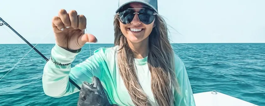 A teen holds up a fish she caught.