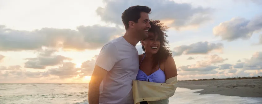 Couple embraces on the beach at sunset.