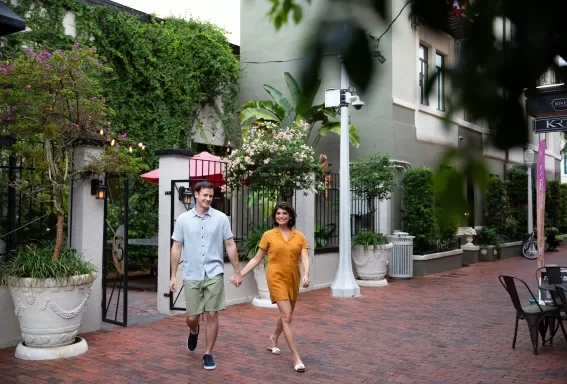 A couple holding hands walking down a sidewalk 