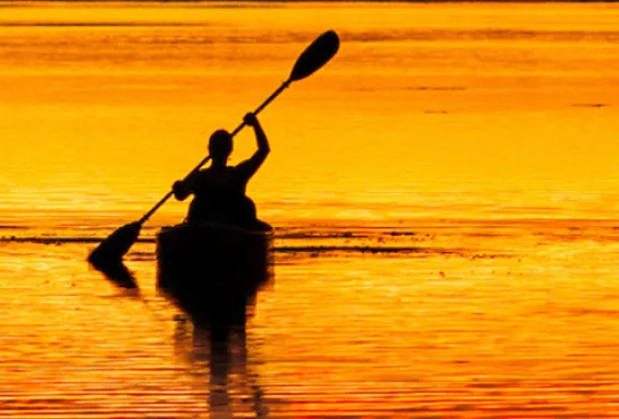 A man paddles across Big Pine Sound at sunset