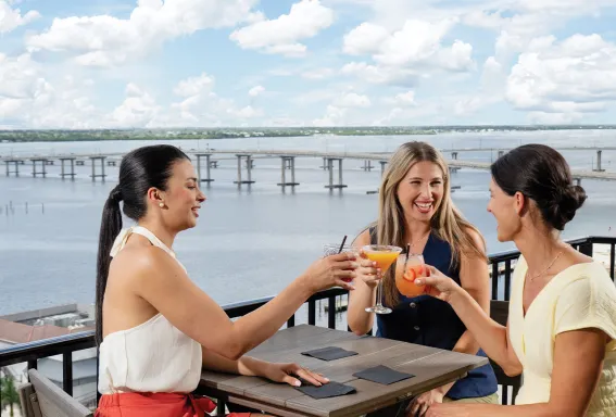 Friends toast drinks at a rooftop bar.