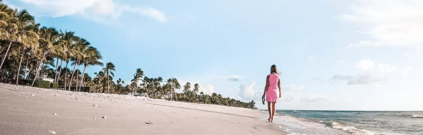 A woman walks down the beach leaving footprints in the sand