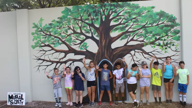 tree with children in front of mural