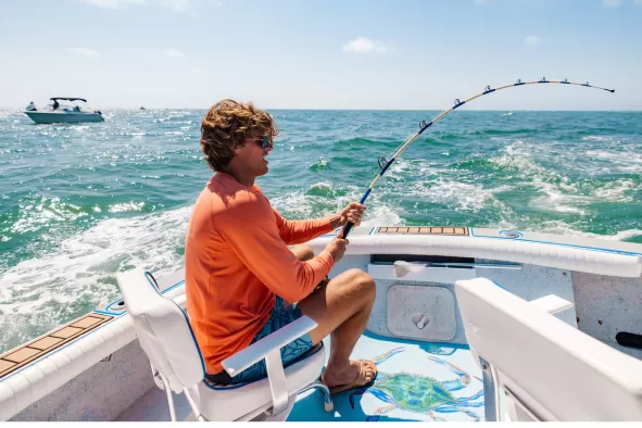 A man reels in a fish from a boat